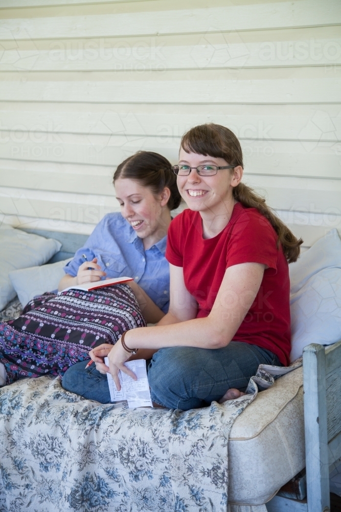 Two teen daughters talking together on the verandah - Australian Stock Image