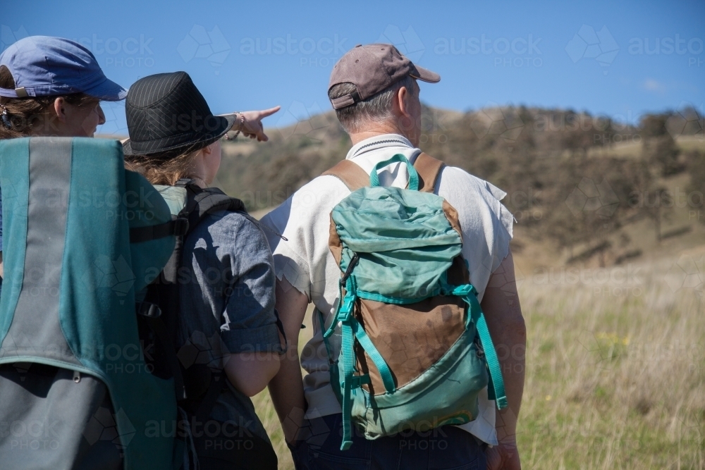 Two teen daughters with their dad about to go walking through a paddock - Australian Stock Image