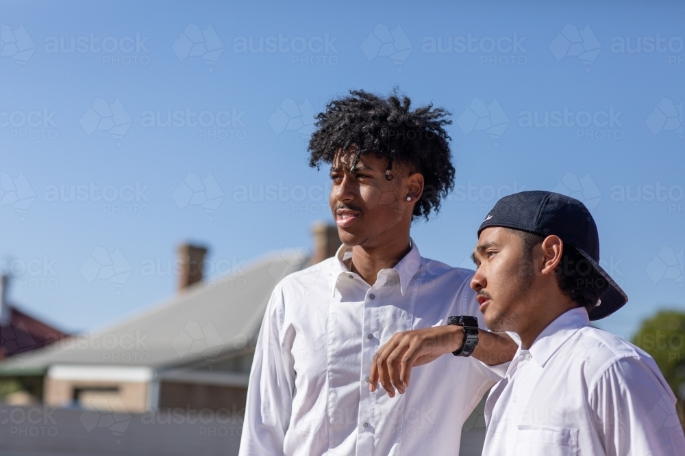 two teenage boys in white shirts looking off camera - Australian Stock Image
