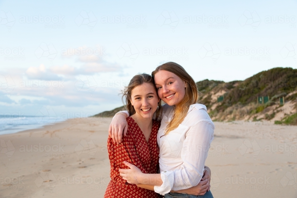 Two teenage girls embracing on the beach - Australian Stock Image