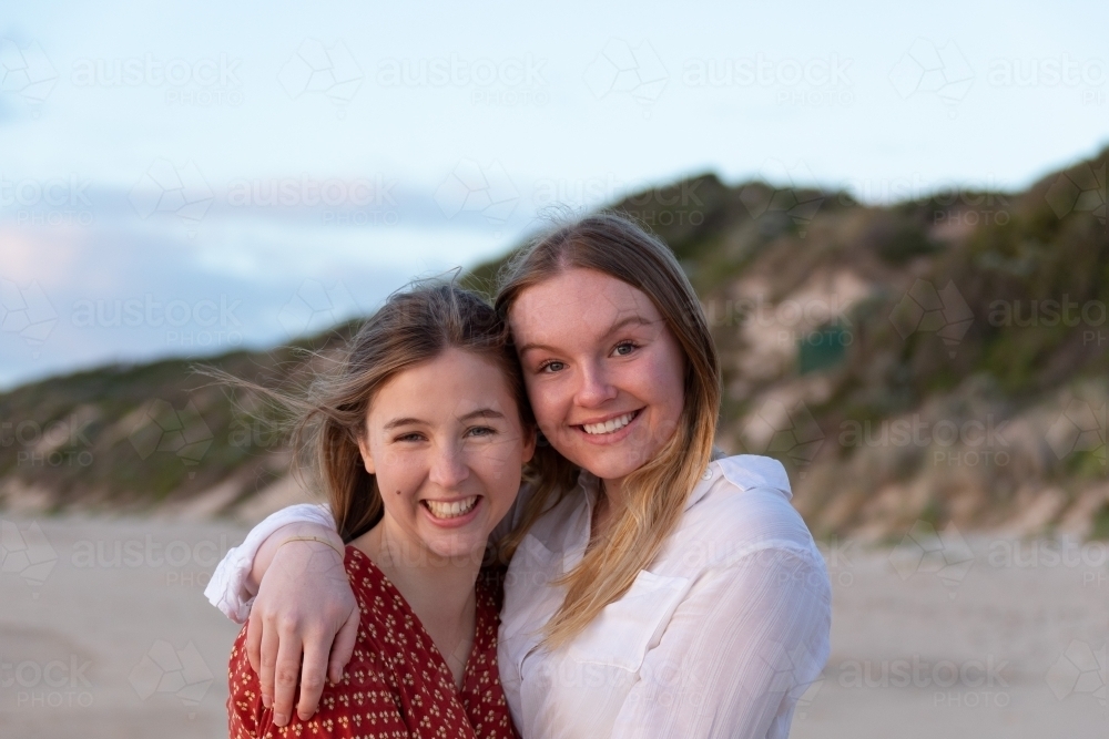 Two teenage girls embracing on the beach - Australian Stock Image