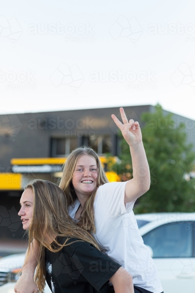 Two teenage girls, one making peace sign - Australian Stock Image