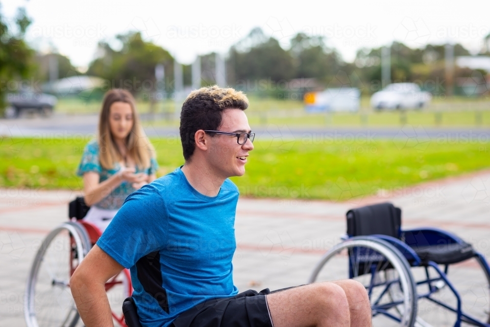 Image of two teenagers in wheelchairs beside an empty wheelchair