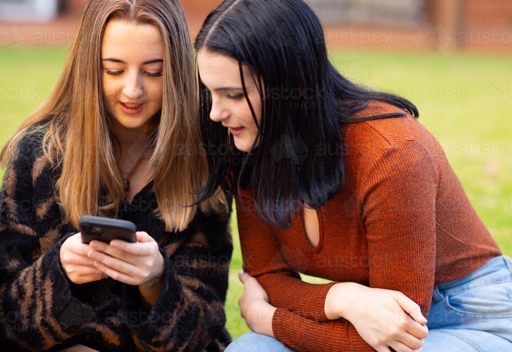 two teenagers looking at a smartphone - Australian Stock Image