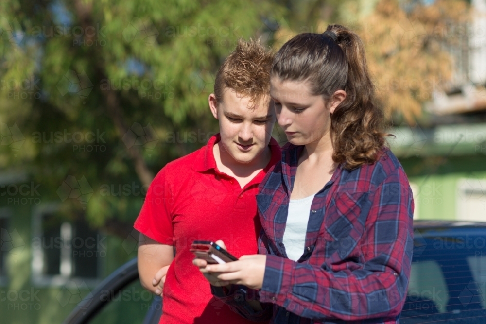 Two teenagers looking at mobile phone - Australian Stock Image