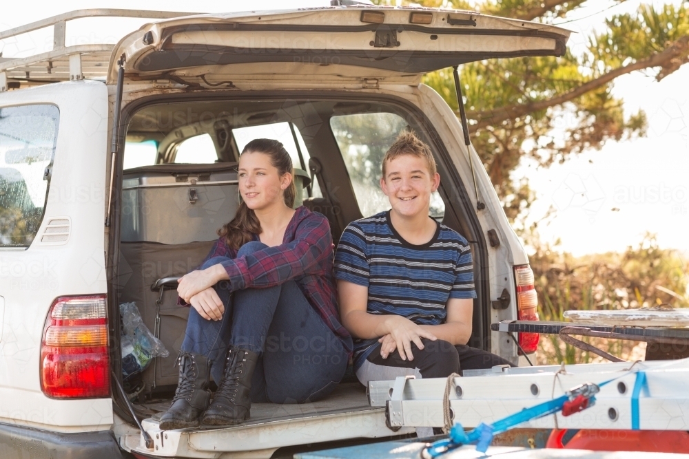 Two teenagers sitting on tailgate of 4WD - Australian Stock Image