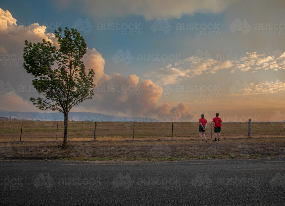 Two teens looking at the smoke of a bushfire in the distance - Australian Stock Image
