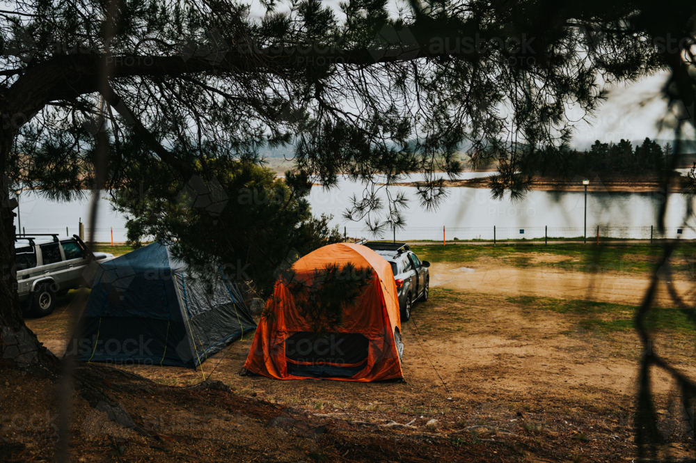 two tents on a camping site in front of a lake on a winter day - Australian Stock Image