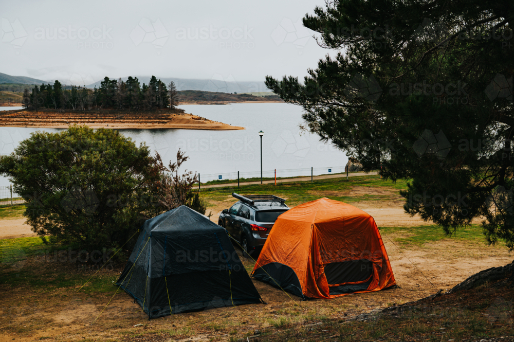 two tents on a camping site in front of a lake on a winter day - Australian Stock Image