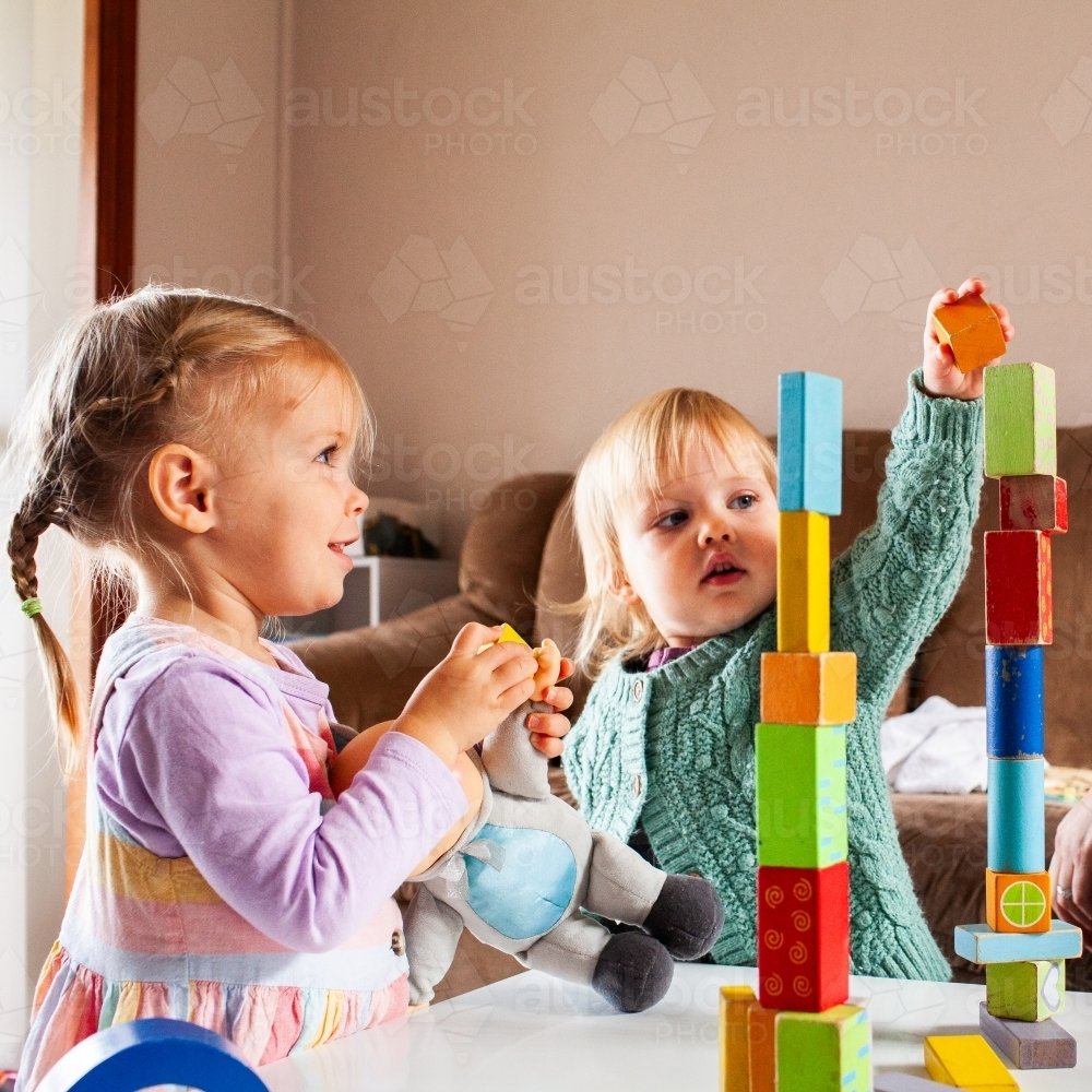 Two toddler friends building towers with brightly coloured blocks inside - Australian Stock Image