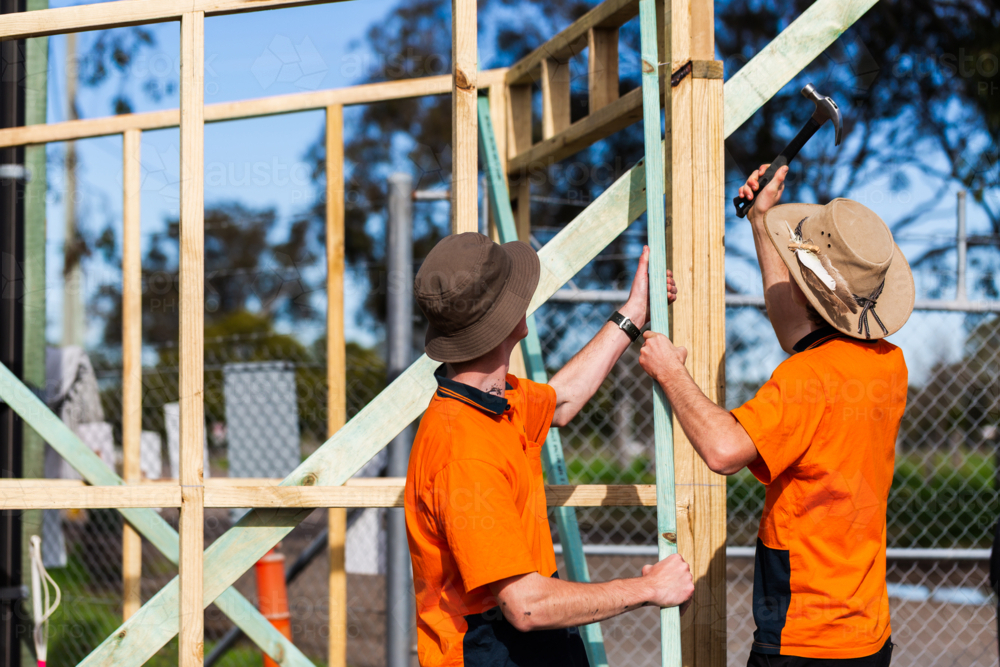 Two trade apprentice workers learning through hands on course building frame of ticket booth - Australian Stock Image