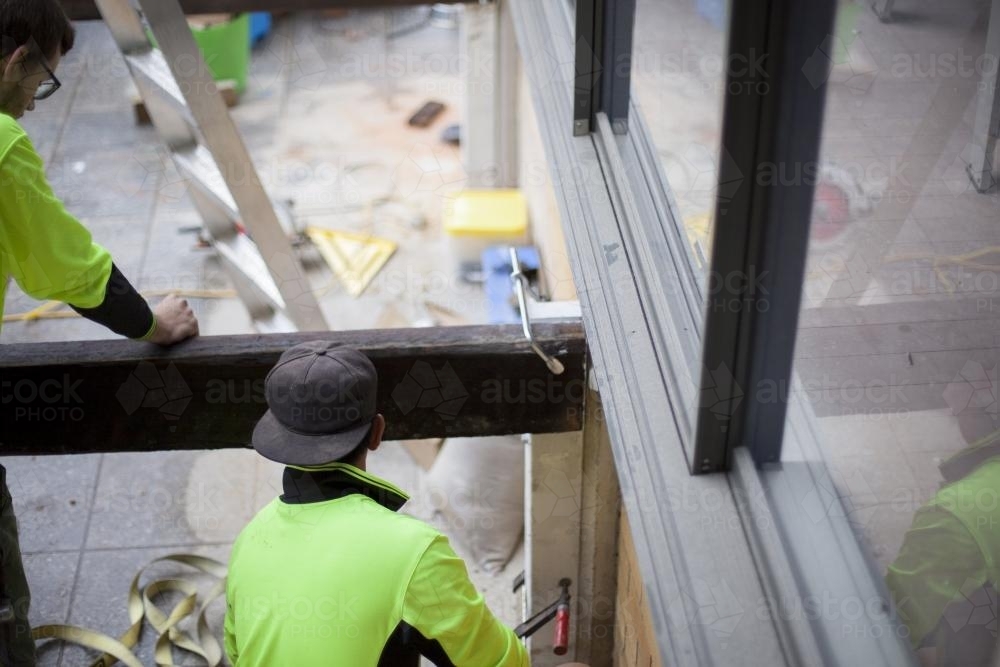 Two tradesmen building a deck on a home renovation site. - Australian Stock Image