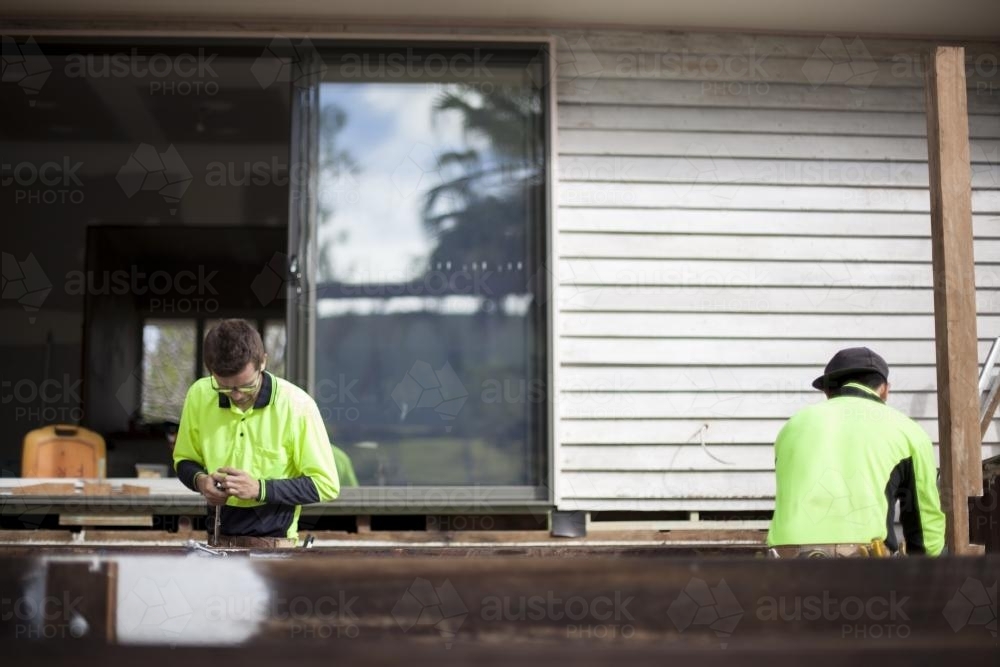 Two tradesmen work on home renovations. - Australian Stock Image