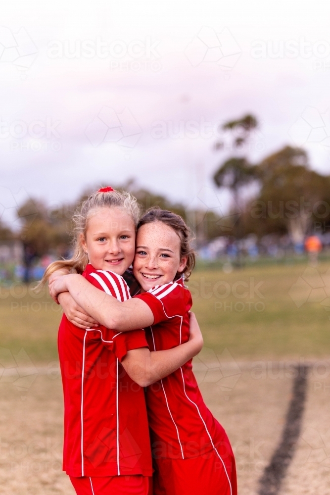Two tween football players hug at practise - Australian Stock Image