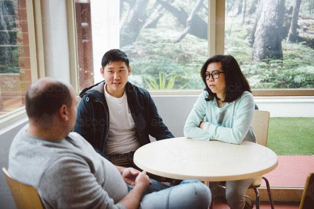 Two university students having a discussion with tutor - Australian Stock Image