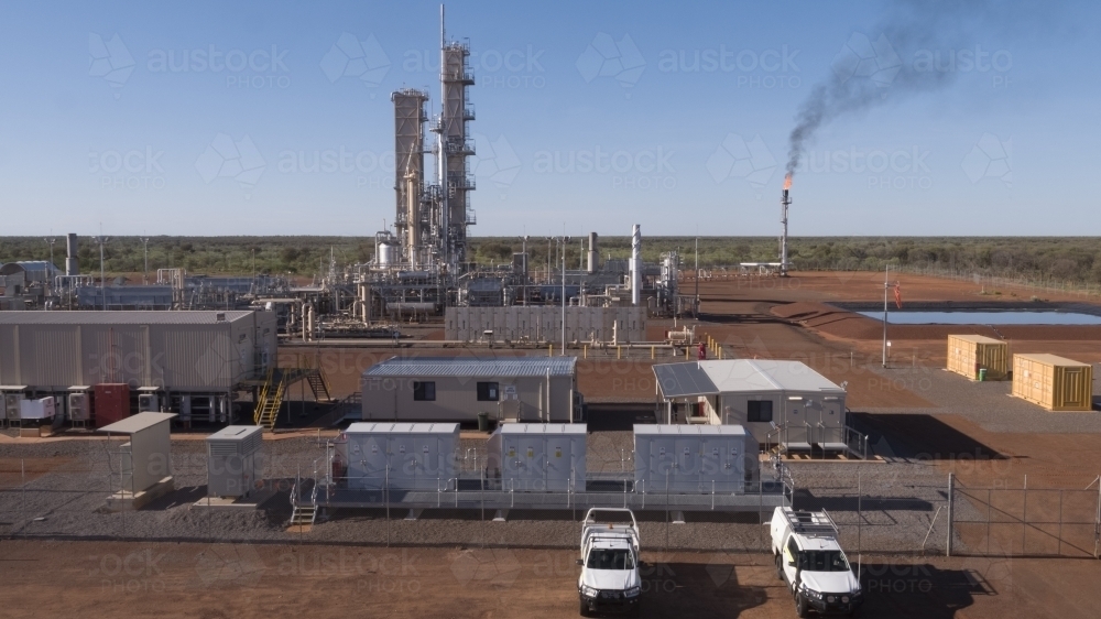 Two white workers cars parked outside a power plant with a smoking flue-gas stack - Australian Stock Image