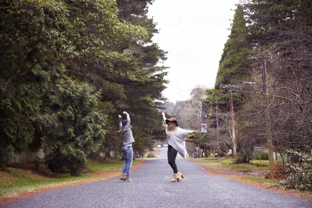Two women dancing on empty road - Australian Stock Image