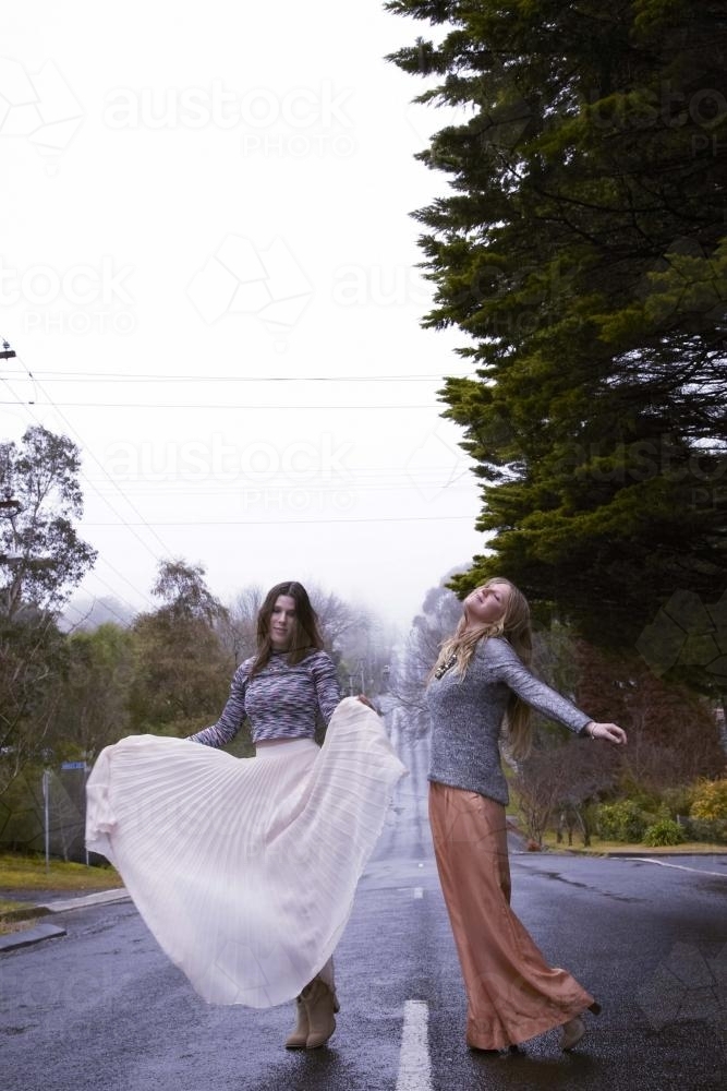 Two women dancing on empty road - Australian Stock Image
