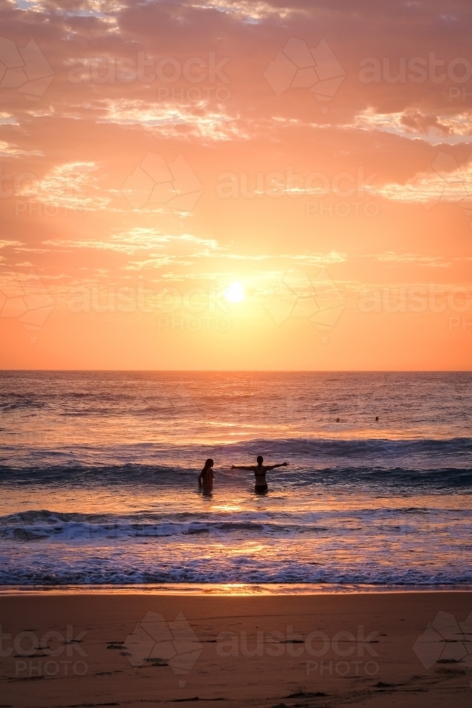 Two women in the water at sunrise - Australian Stock Image