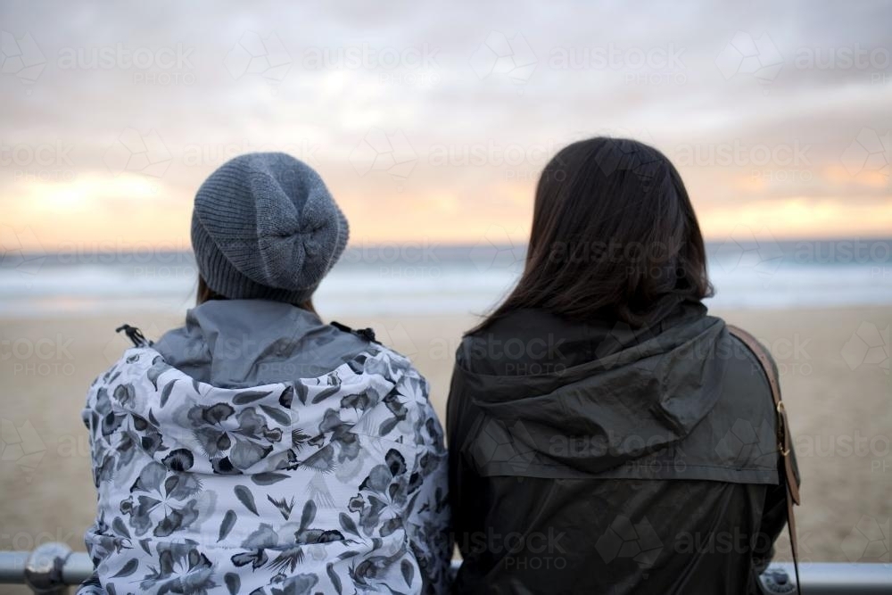 Two women looking out at the beach at sunset - Australian Stock Image