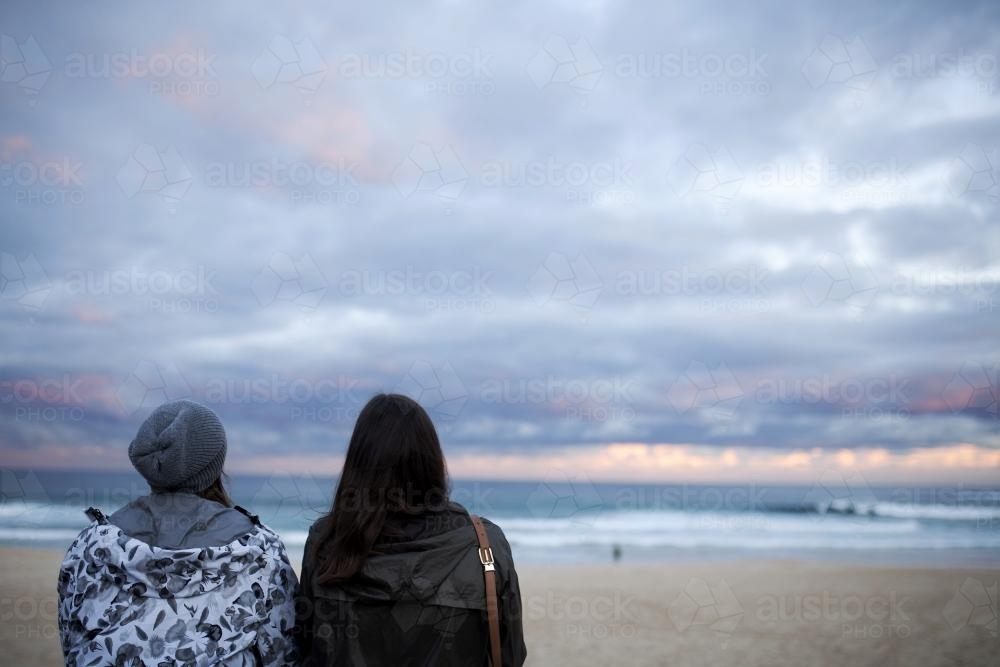 Two women looking out at the beach at sunset - Australian Stock Image
