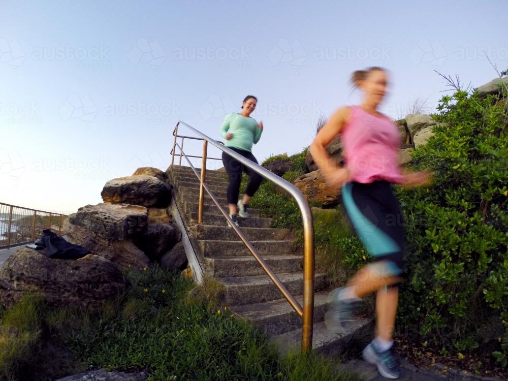 Image of Two women running down stairs Austockphoto