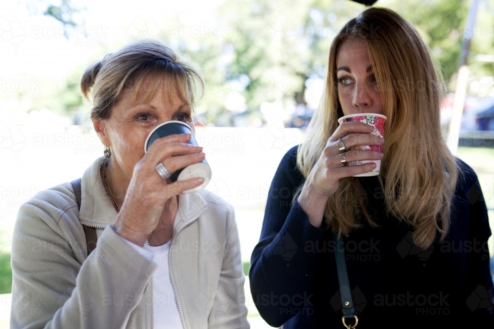 Two women sipping from their coffee cups - Australian Stock Image