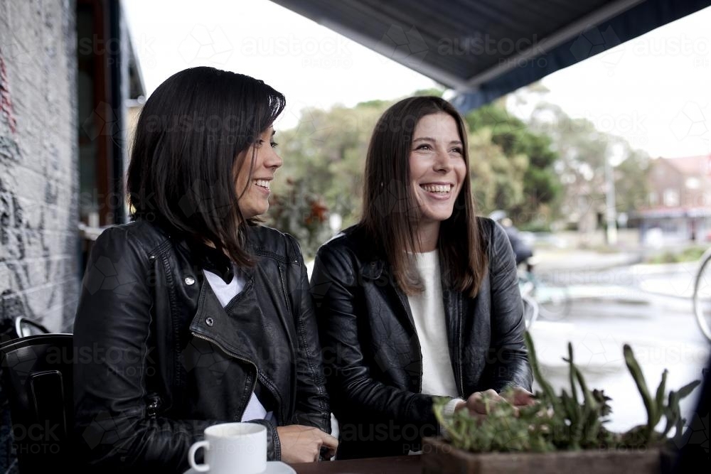 Two women sitting and laughing at a cafe - Australian Stock Image