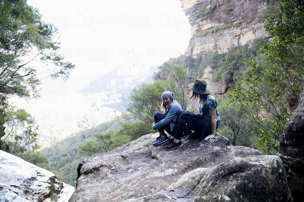 Two women sitting on rocky outcrop - Australian Stock Image