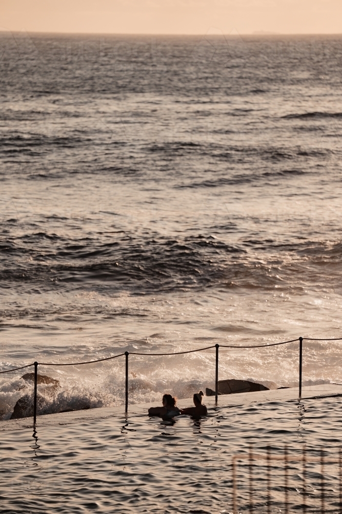 Two women swimming in the Bronte Ocean Pool (Bronte Baths) at sunrise - Australian Stock Image