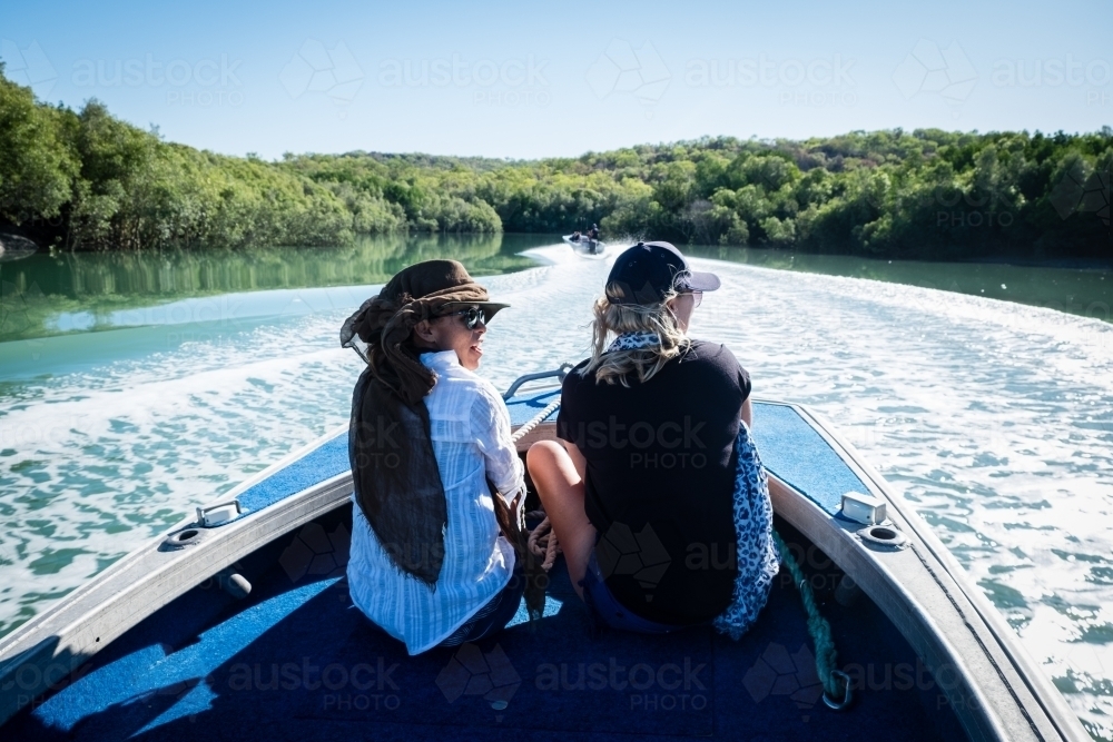 Two women travelling in a small power raft on a ocean inlet dressed with sun protection - Australian Stock Image