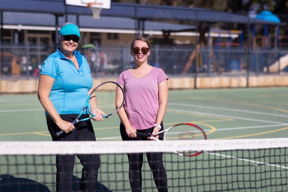 two women with tennis racquets standing on tennis court - Australian Stock Image