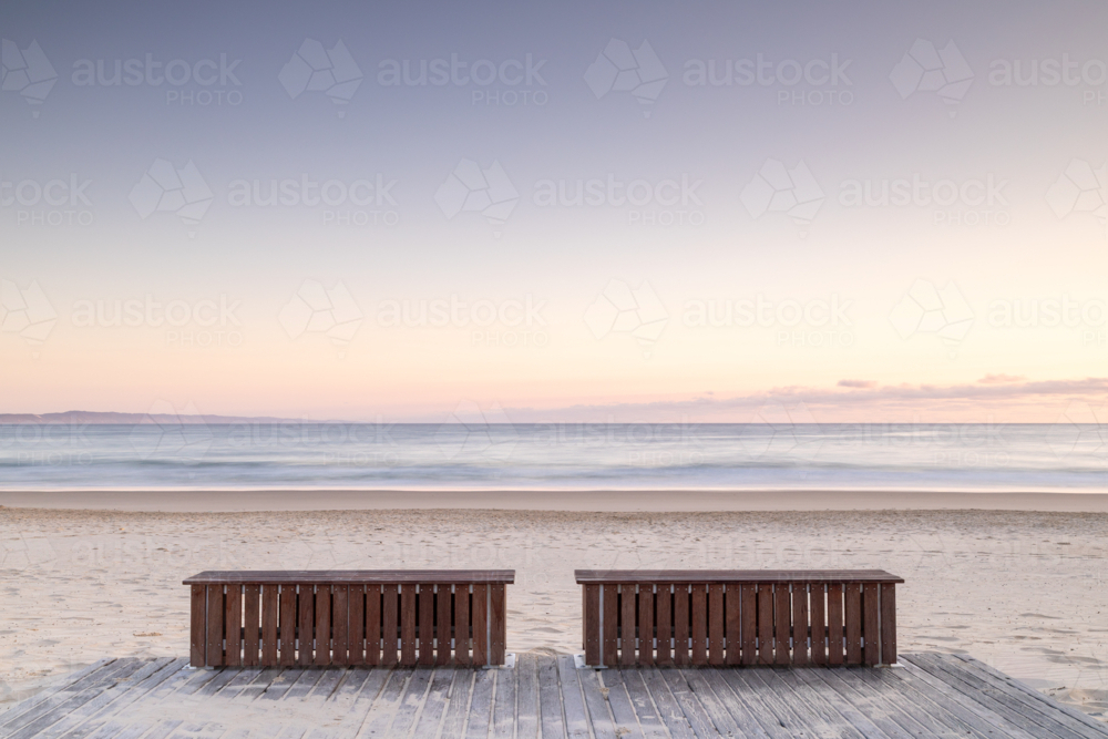 Two wooden bench seats on boardwalk at the beach - Australian Stock Image