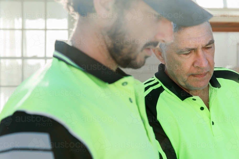 Two workers discussing  at a construction site - Australian Stock Image