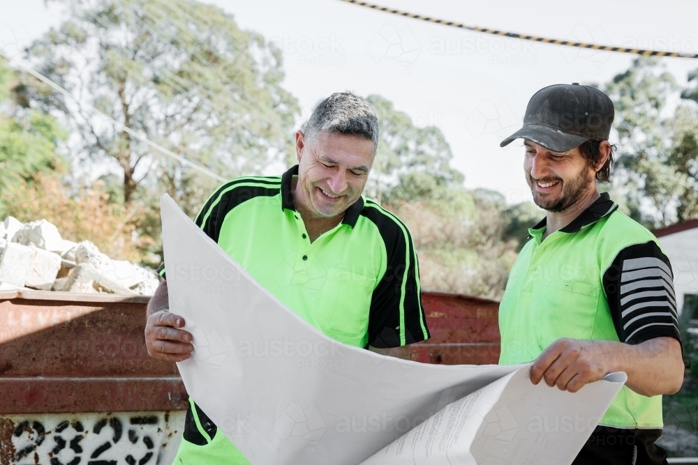 Two workers discussing plans on a broadsheet - Australian Stock Image