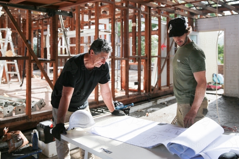 Two workers inspecting plans on a building site - Australian Stock Image