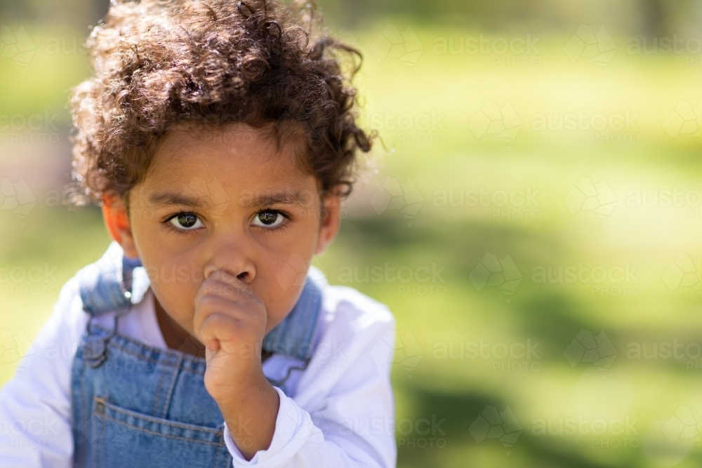 Two year old child sucking thumb outdoors - Australian Stock Image