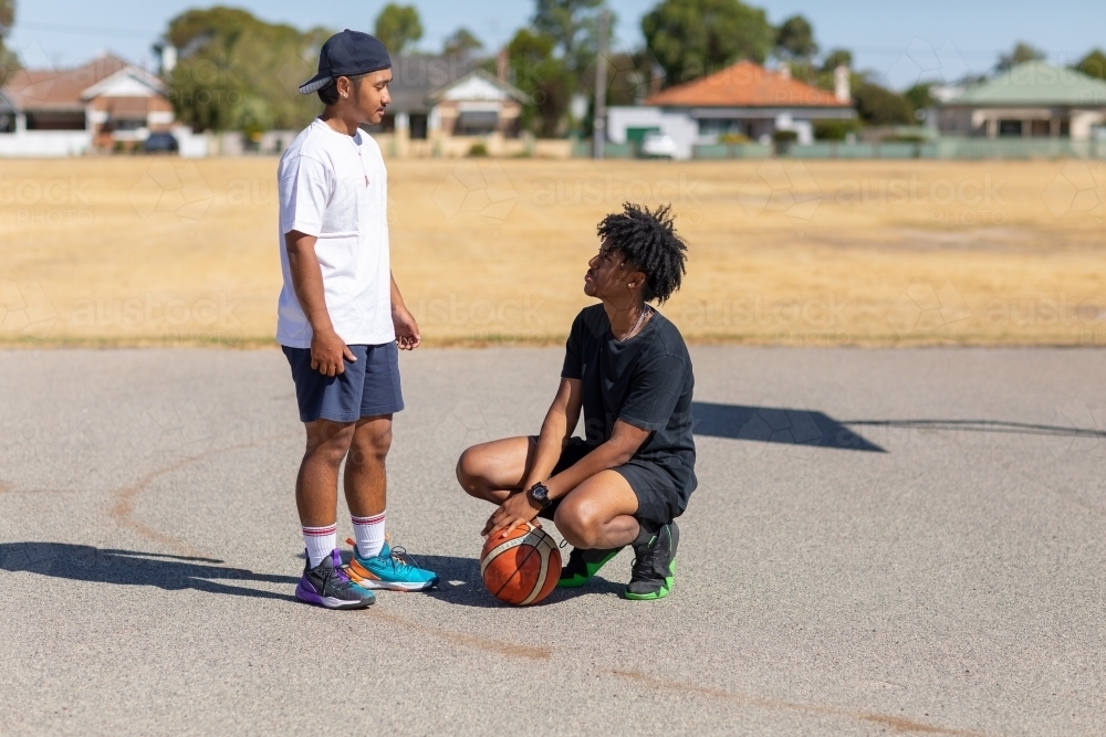 Two young blokes on outdoor basketball court - Australian Stock Image