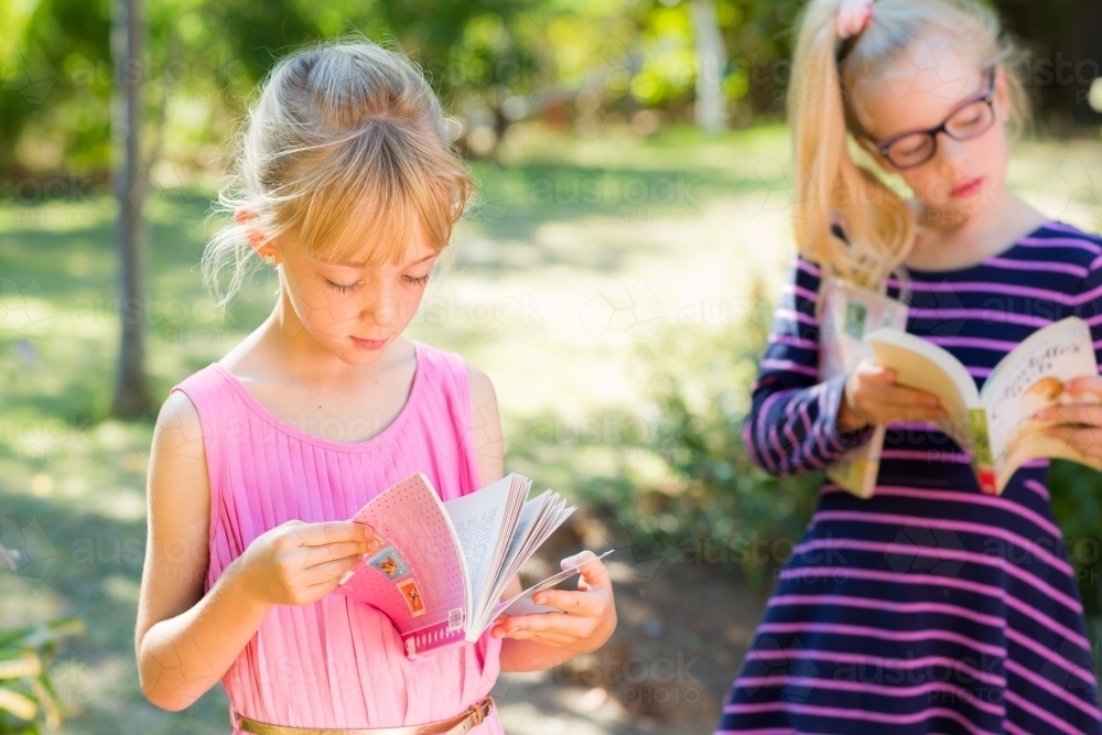 Two young blonde girls reading books - Australian Stock Image