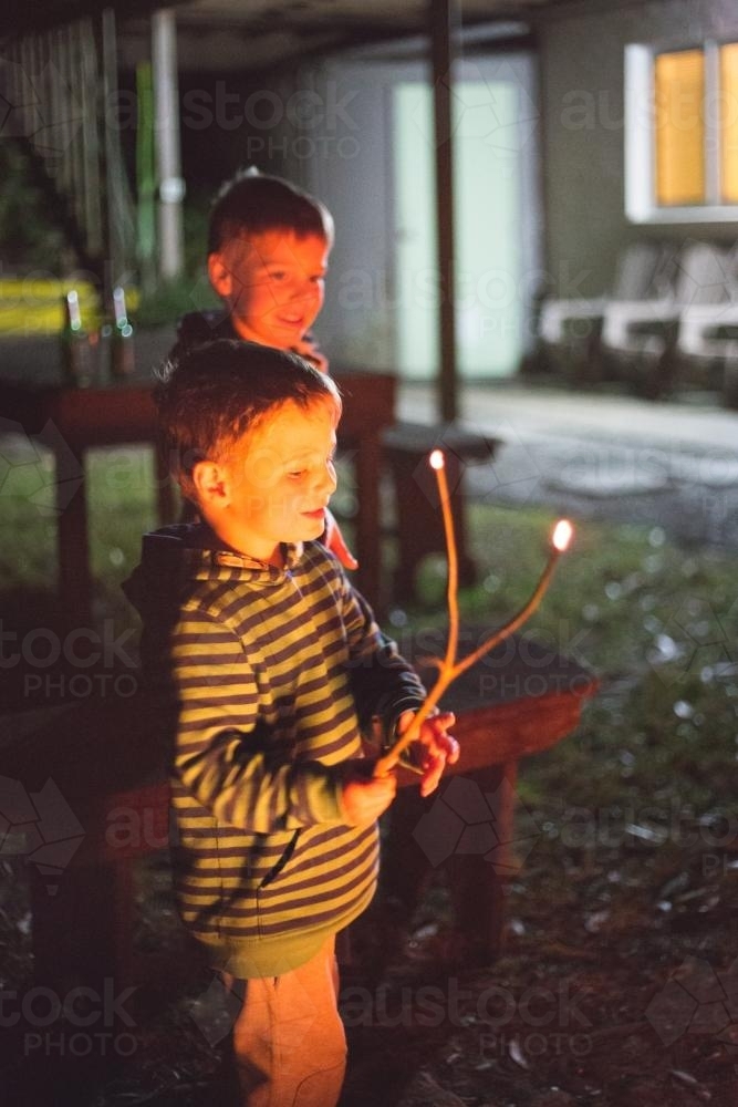 Two young boys in backyard looking at outdoor fire - Australian Stock Image
