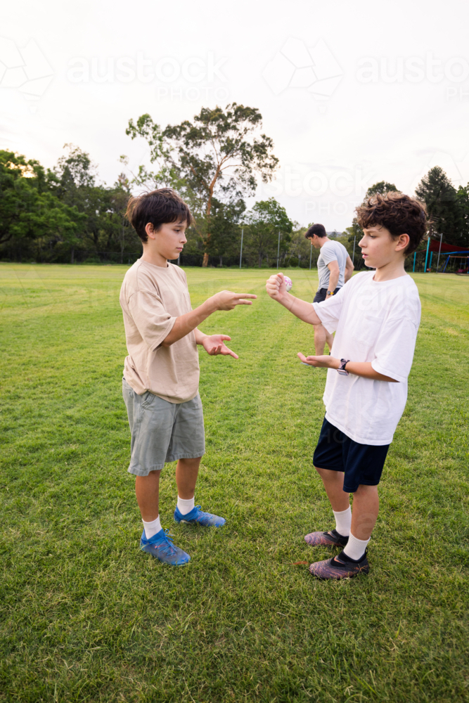 Two young boys Playing Rock‑Paper‑Scissors in a green grassy soccer field - Australian Stock Image