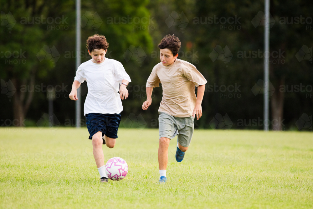 Two young boys playing soccer on a grassy field - Australian Stock Image