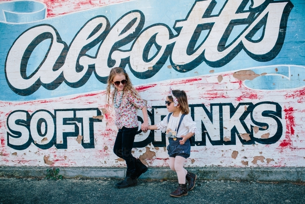 Two young fashionable urban kids with sunglasses and painted wall - Australian Stock Image