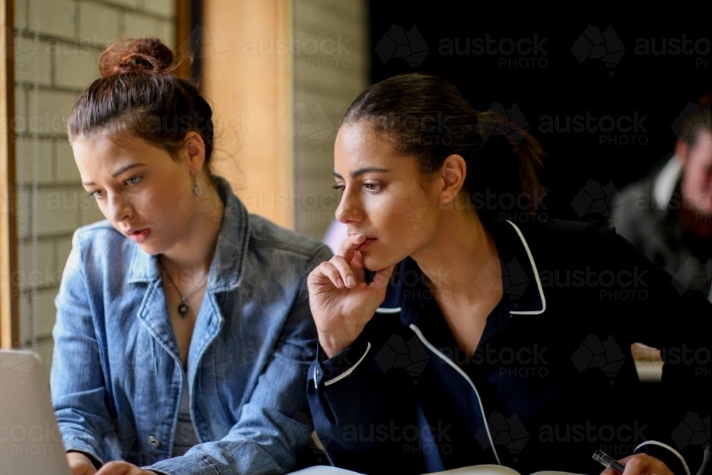 Two young females sitting at a desk in a classroom looking at a computer - Australian Stock Image
