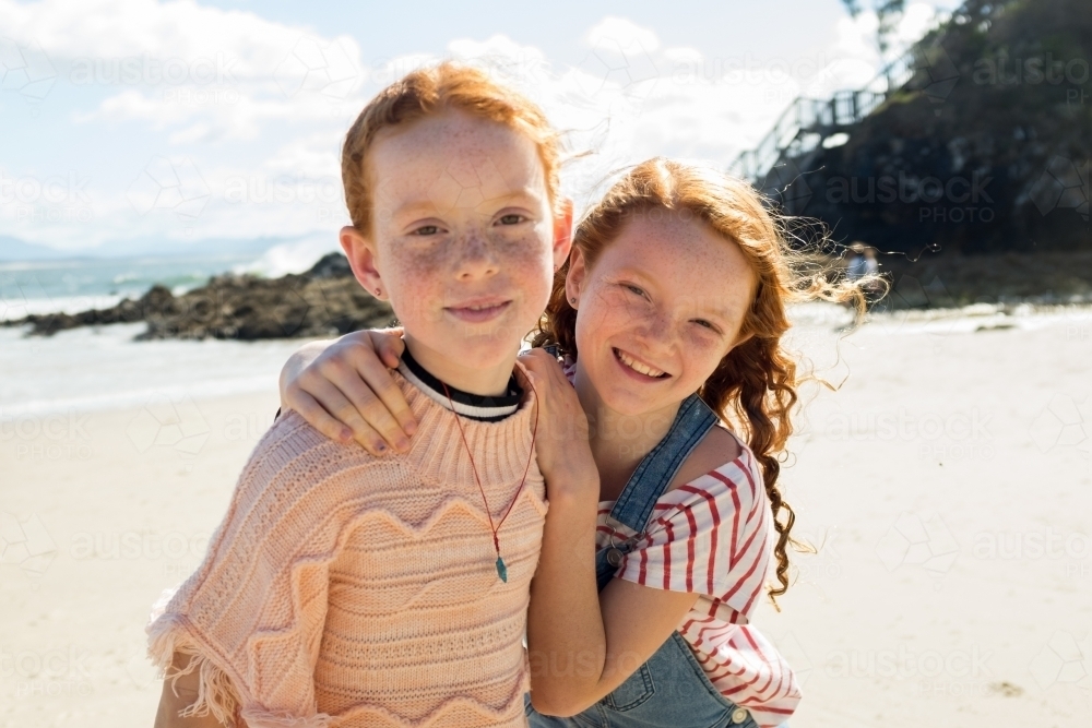 Two young girls hugging and smiling at the beach - Australian Stock Image