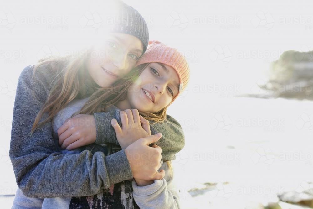 Two young girls hugging each other by the ocean - Australian Stock Image