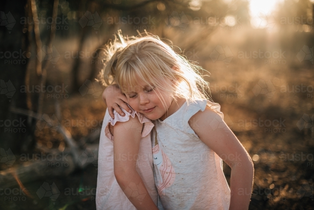 Two young girls hugging outside in last light - Australian Stock Image
