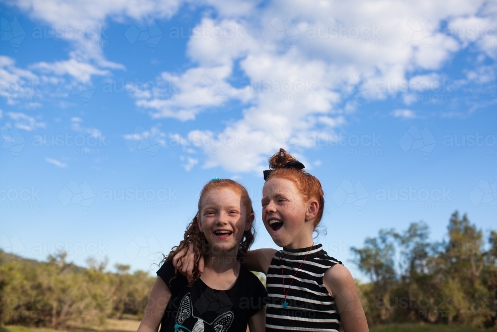 Two young girls outside laughing together - Australian Stock Image