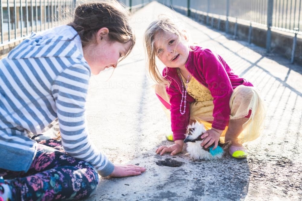 Two young girls sitting on a bridge - Australian Stock Image