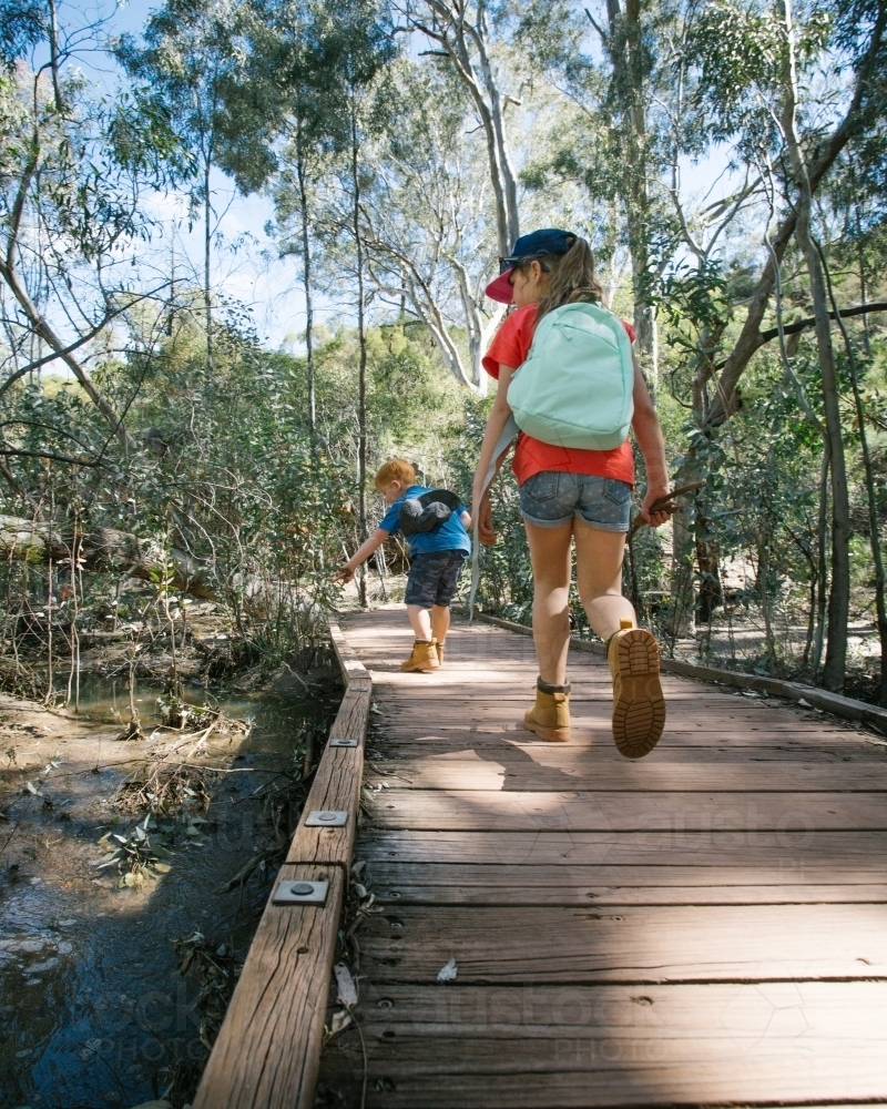 Two young kids going on a bush walk along a wooden boardwalk - Australian Stock Image
